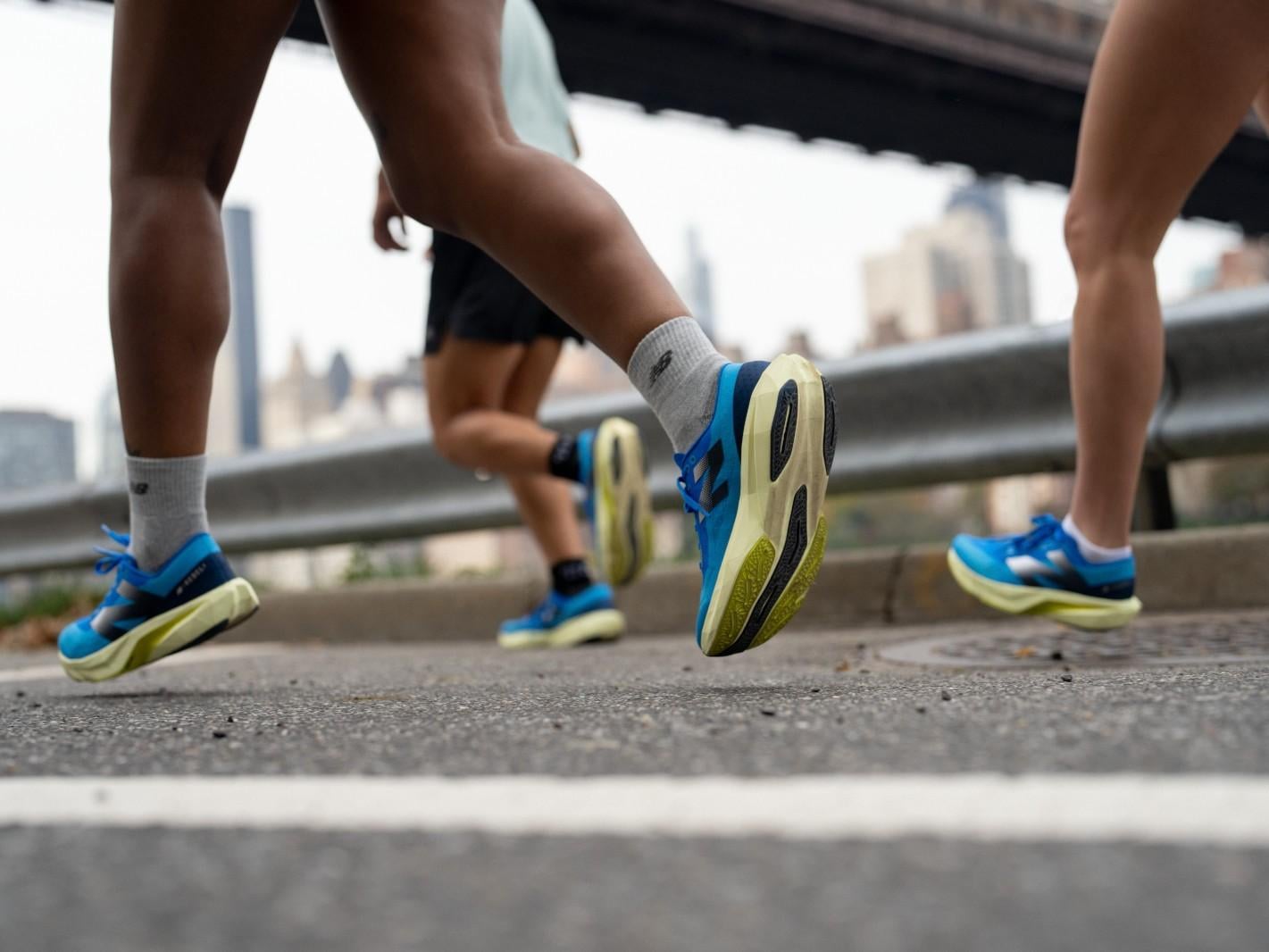 Ein junger Mann mit Sonnenbrille und einer warmen Mütze lächelt in einer schneebedeckten Landschaft. Im Hintergrund sind verschneite Bäume sichtbar.