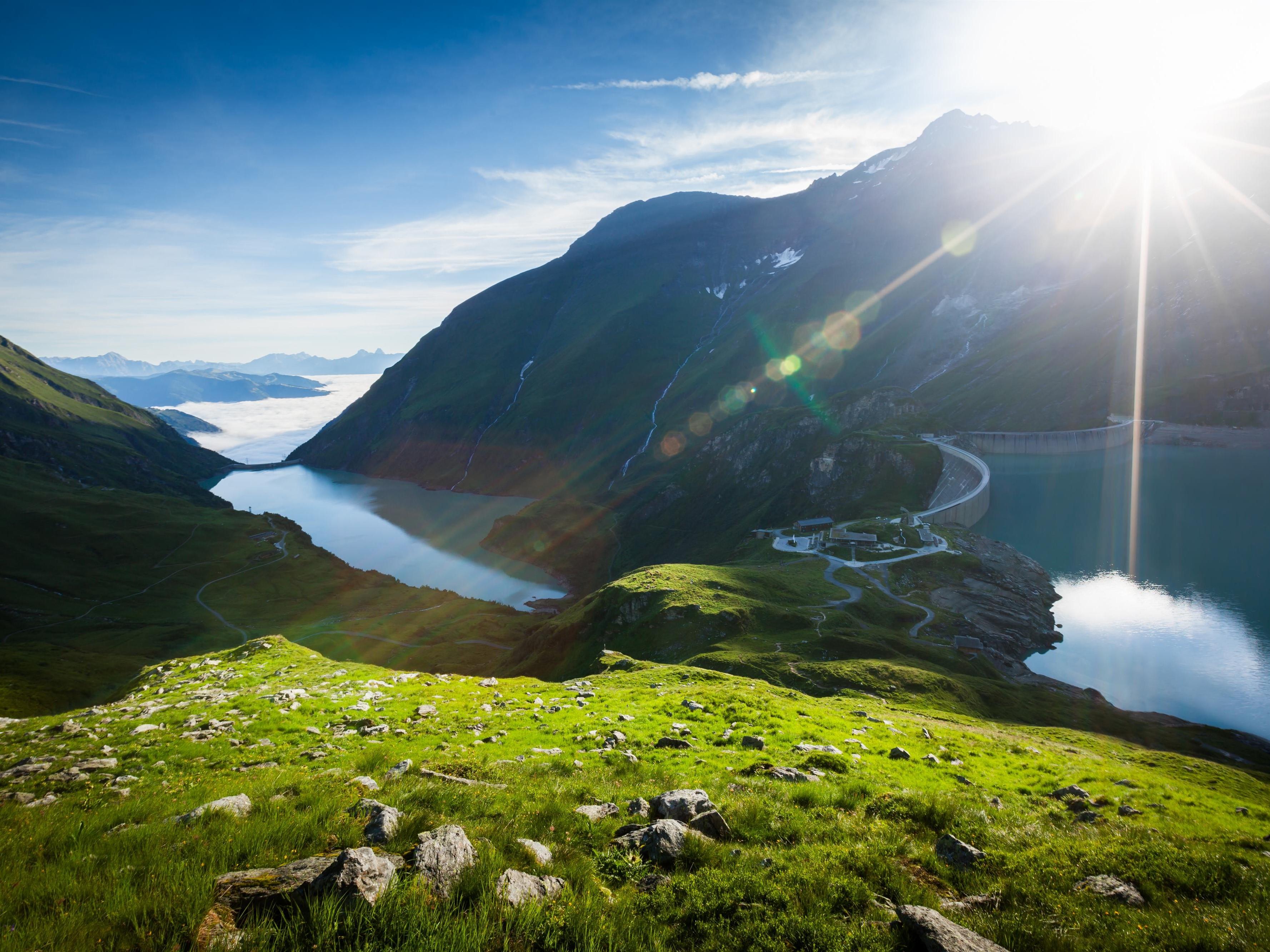 Eine wunderschöne Berglandschaft mit einem klaren Wassersee und sonnigem Himmel. Die saftigen grünen Wiesen umgeben die ruhigen Gewässer.