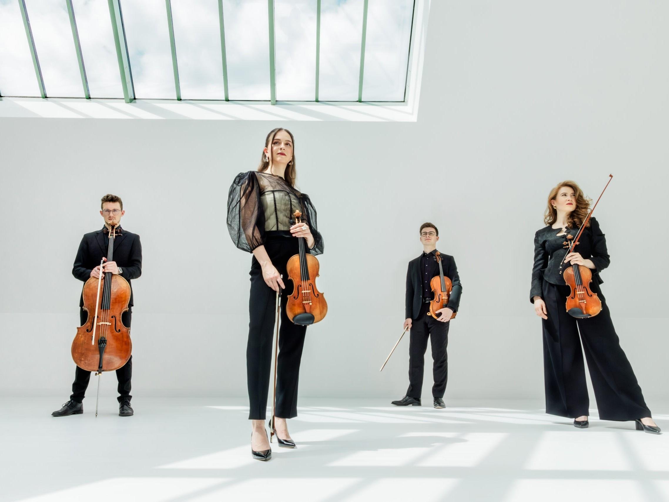 An elegant group of musicians is playing in a bright, modern space. The simple, white design and large windows create a harmonious atmosphere.
