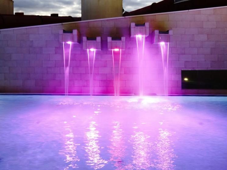 Eine Person steht im Wasser und spritzt Wasser mit den Händen. Im Hintergrund ist ein schöner Sonnenuntergang zu sehen.