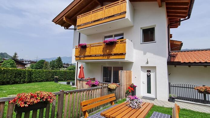 A beautiful house with a balcony and blooming plants. The garden is green and inviting, perfect for relaxing days outdoors.