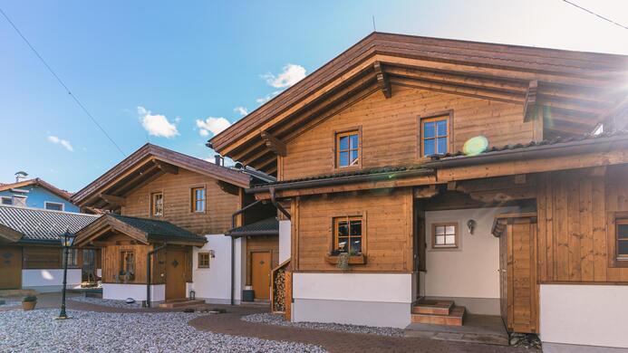 Zwei charmante Holzh&auml;user in einer ruhigen Umgebung. Die Geb&auml;ude haben typisch alpine Architektur und sind von klarem Himmel umgeben.