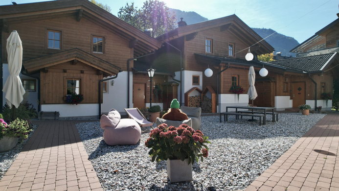 Eine gem&uuml;tliche Gartenanlage mit Holzapartments und bl&uuml;henden Blumen. Der Raum ist hell erleuchtet und l&auml;dt zum Entspannen ein.