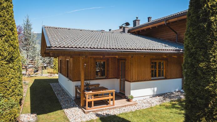 Ein gem&uuml;tliches Holzhaus mit einem gut gepflegten Garten und Rasenfl&auml;chen. Die klare blaue Himmel macht die Atmosph&auml;re einladend.