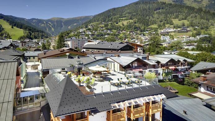 Eine malerische Berglandschaft mit traditionellen Chalets und gr&uuml;nen H&uuml;geln. Der klare Himmel und die gem&uuml;tliche Atmosph&auml;re laden zum Entspannen ein.