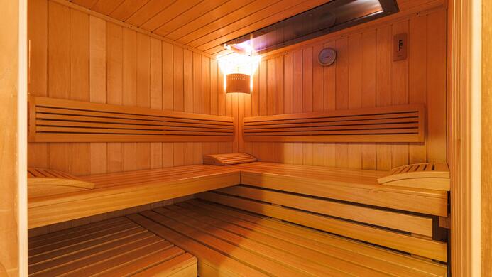 Eine gem&uuml;tliche Sauna mit Holzbank und sanfter Beleuchtung. Der Raum strahlt W&auml;rme und Entspannung aus.