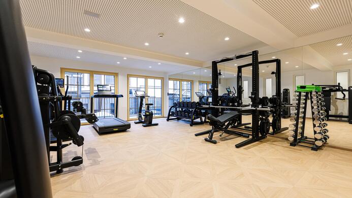 Ein modernes Fitnessstudio mit verschiedenen Trainingsger&auml;ten. Der Raum ist hell und ger&auml;umig, ideal f&uuml;r sportliche Aktivit&auml;ten.