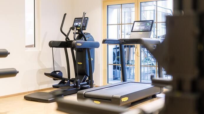 Ein modernes Fitnessstudio mit verschiedenen Trainingsger&auml;ten. Im Hintergrund sind ein Laufband und ein Crosstrainer zu sehen.