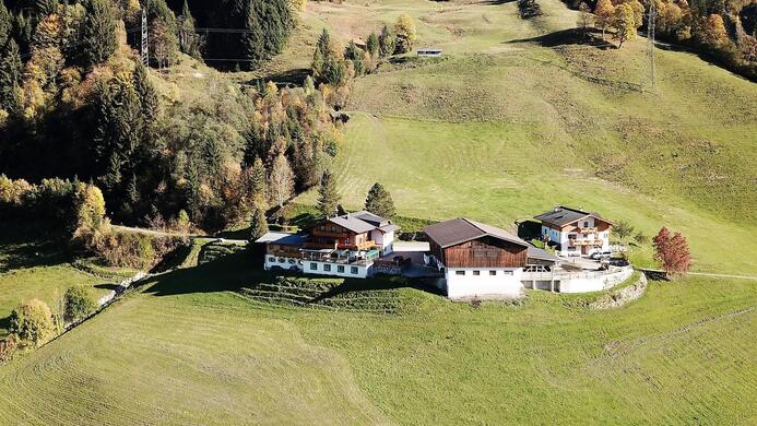 Ein malerisches Bauernhaus inmitten gr&uuml;ner Wiesen und umgeben von B&auml;umen. Die ruhige Landschaft zeigt sanfte H&uuml;gel und eine entspannte Atmosph&auml;re.