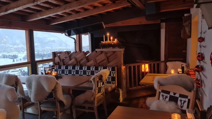 Ein gem&uuml;tliches Restaurant mit Holzelementen und warmem Licht. Der Raum hat einen sch&ouml;nen Ausblick auf die winterliche Landschaft.